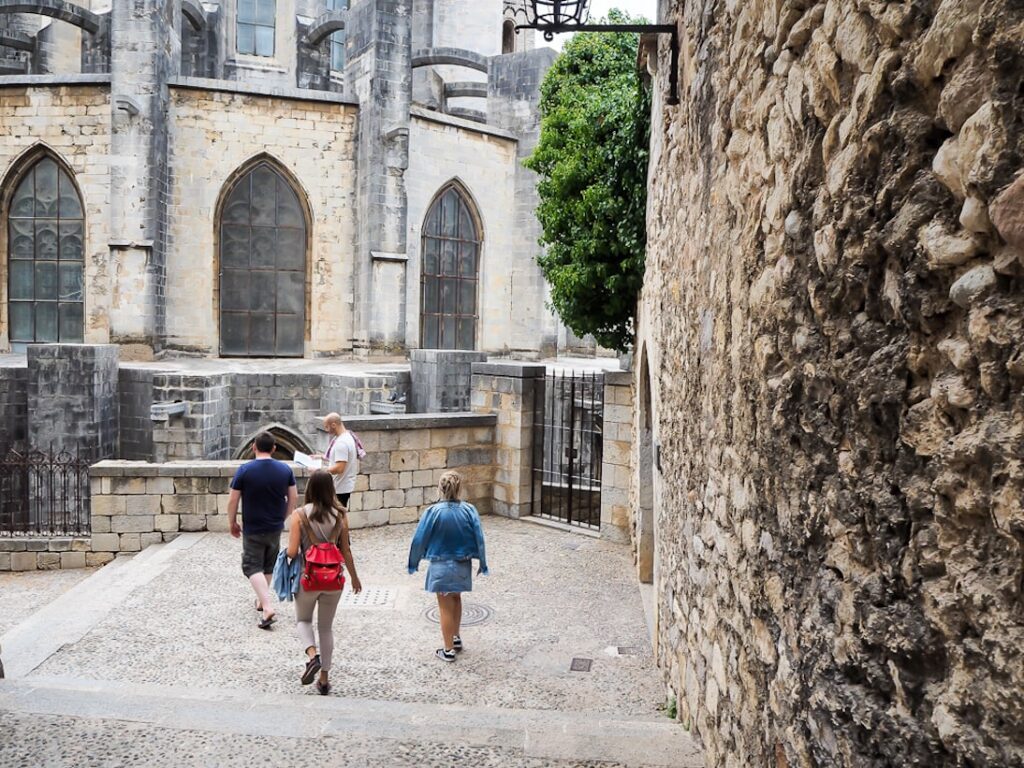 grupo de personas en un tour a pie detrás de la catedral de Girona rodeados de un ambiente medieval